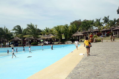 People playing in swimming pool against sky