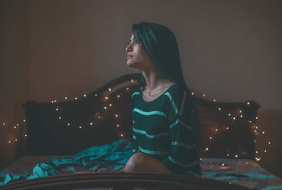 Young woman sitting on bed at home