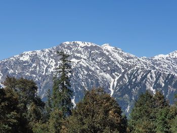 Low angle view of snowcapped mountains against clear blue sky