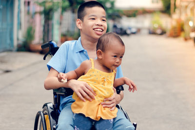 Disable boy holding cute sister while sitting on wheelchair