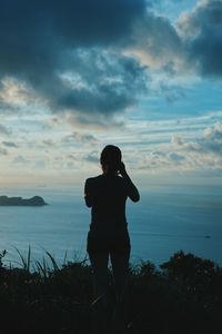 Rear view of man looking at sea against sky