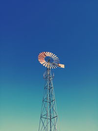 Low angle view of american-style windmill against blue sky