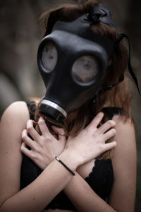 Woman wearing gas mask while covering chest