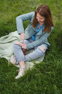 Low section of young woman sitting on grassy field