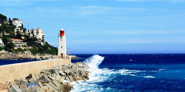 Lighthouse on pier by sea against sky