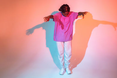 Full body of african american teen girl performing urban dance movement in bright studio