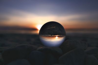 Close-up of glass orb in front of a beautiful sunset.