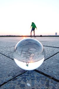 Close-up of crystal ball on water against clear sky during sunset