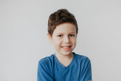 A preschool boy in a blue t-shirt on a light background shows a thumbs up. high quality photo