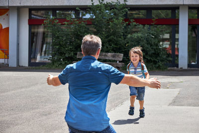 Dad meets a child, a boy from school. the father opens his arms for hugs. children come home