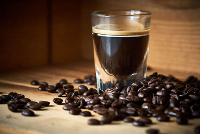 Black coffee with roasted beans on table