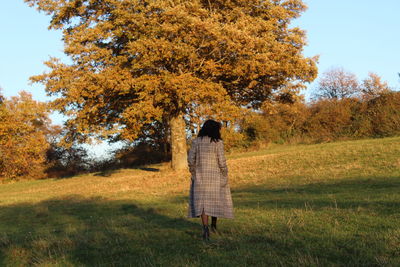 Rear view of woman standing on field during autumn