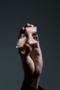 Cropped hand holding mirror with reflection of woman eyes against gray background