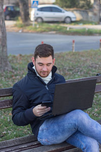 Young man using mobile phone while sitting outdoors