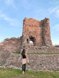 Woman standing by old ruin against sky