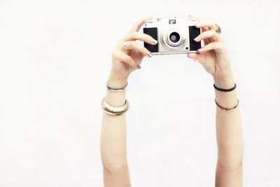 Midsection of woman photographing against white background