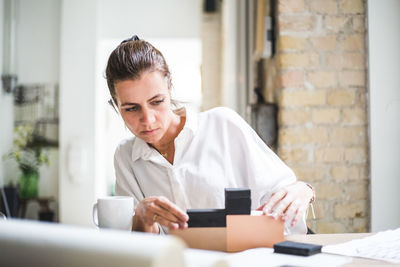 Female design professional working with boxes while sitting at home office