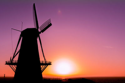 Silhouette windmill on field against sky during sunset