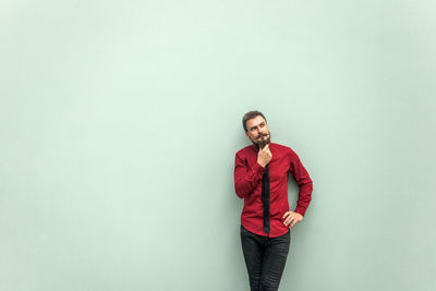 Portrait of young man standing against wall