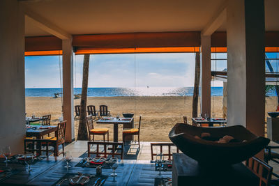 Chairs and tables at restaurant by sea against sky