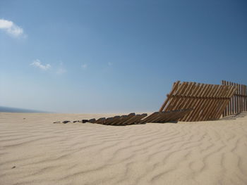 Sand dunes at beach against sky