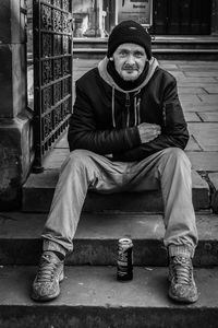 Full length portrait of young man sitting outdoors