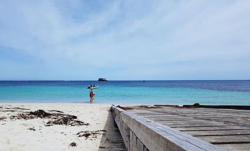 Rear view of man standing on beach against sky