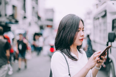 Young woman using mobile phone in city