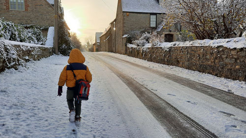 Rear view of man walking on snow covered road