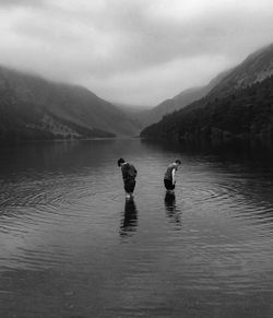 People in lake against sky