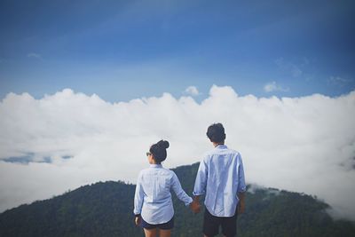 Rear view of couple standing on mountain against sky