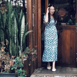 Young woman wearing dress while walking against door