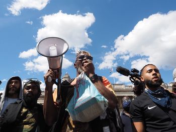 Low angle view of people standing against the sky
