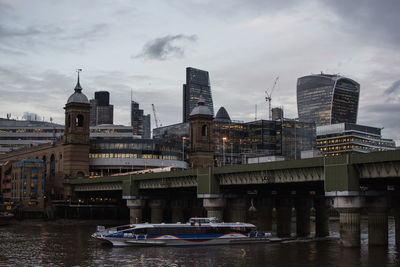 View of city at waterfront against cloudy sky