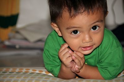 Close-up portrait of cute baby boy lying on bed at home