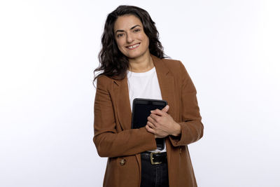 Portrait of a smiling young woman using phone against white background