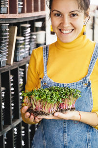 Woman holding box with microgreen, small private business indoor vertical farm. healthy vegetarian