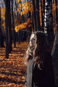 Girl with eyes closed standing amidst trees at forest