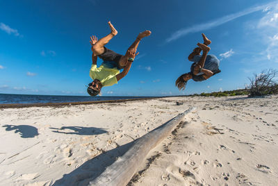 People jumping on beach against sky