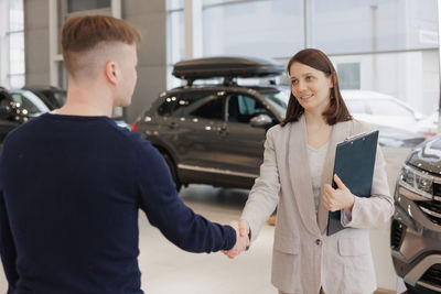 Portrait of young woman standing against car