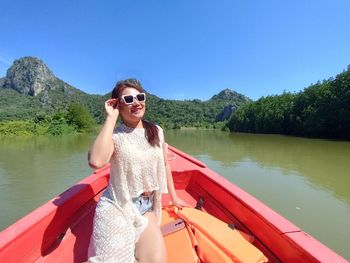 Portrait of young woman standing against lake