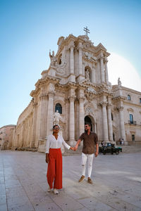 People standing outside historic building against sky