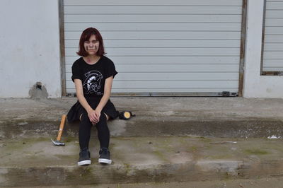 Woman with face paint sitting against shutter