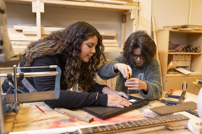 Female technician teaching boy to repair laptop at recycling center