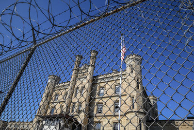 Abandoned historic prison through chain fence