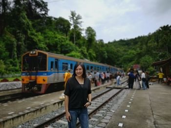 Portrait of smiling woman standing at railroad station platform