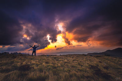 Man standing on field against sky during sunset