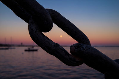 Close-up of rusty chain by sea against clear sky during sunset