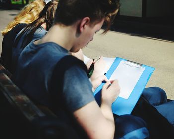 Man writing while sitting on bench