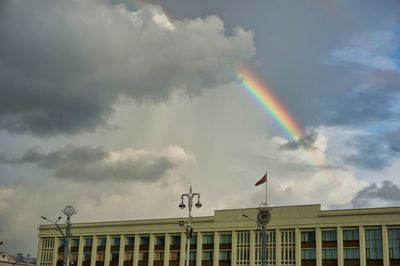 Low angle view of rainbow over city against sky